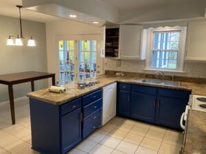 A kitchen with white cabinets on top and blue cabinets on the bottom.